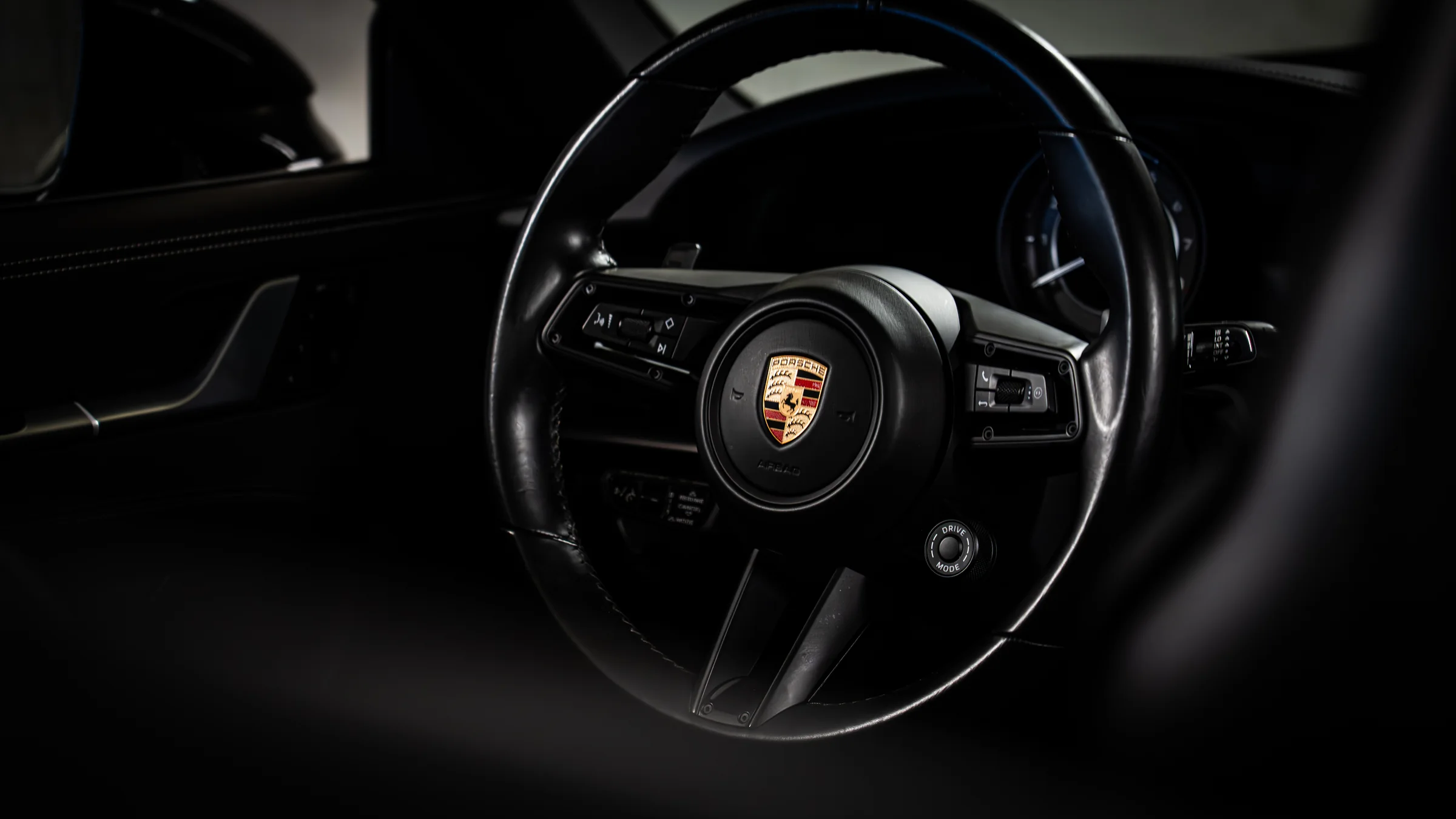 Lenkrad mit Porsche-Wappen im Low-Key-Licht